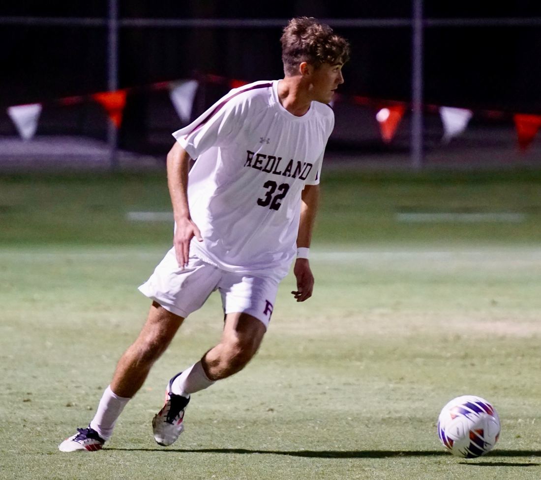 Nicolas dribbling with the ball during a University of Redlands match